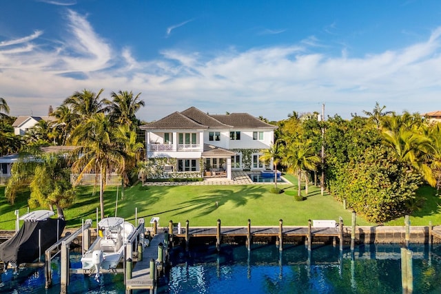 rear view of house with a lawn, a balcony, a patio area, boat lift, and an outdoor pool