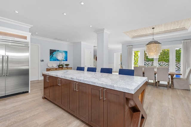 kitchen with a center island, light hardwood / wood-style flooring, built in refrigerator, and crown molding