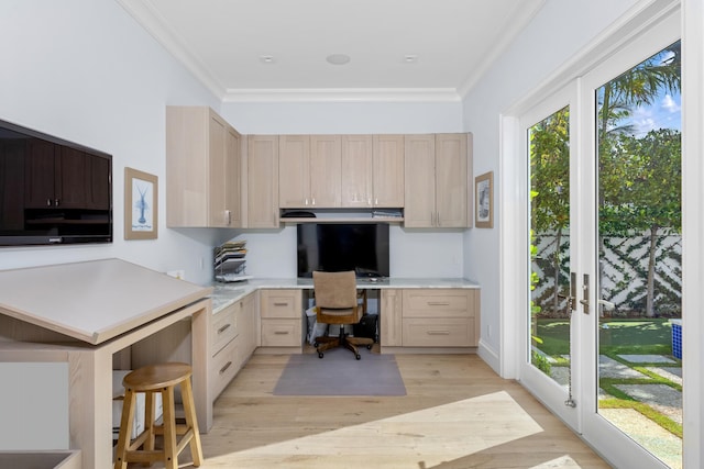 office area with crown molding, built in desk, and light wood-type flooring