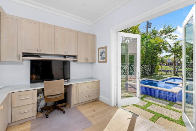 office area with ornamental molding, light wood-type flooring, plenty of natural light, and built in desk