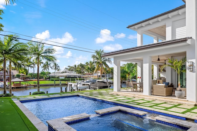 view of swimming pool with a water view, a patio area, an in ground hot tub, and a dock