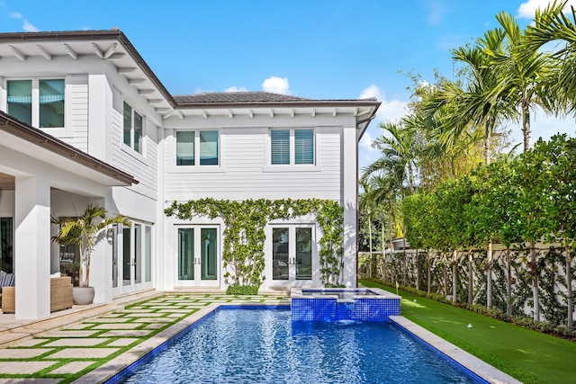 rear view of property featuring french doors, pool water feature, a patio area, and a pool with hot tub