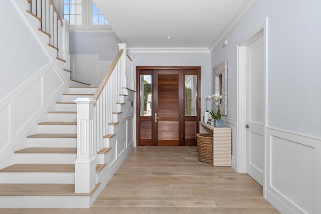 foyer featuring light wood-type flooring and ornamental molding