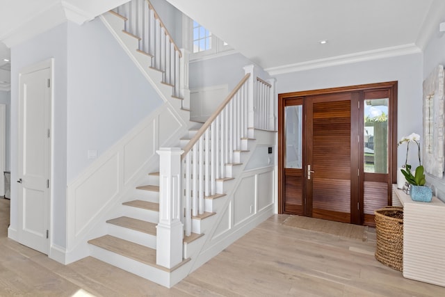 entrance foyer featuring ornamental molding and light wood-type flooring