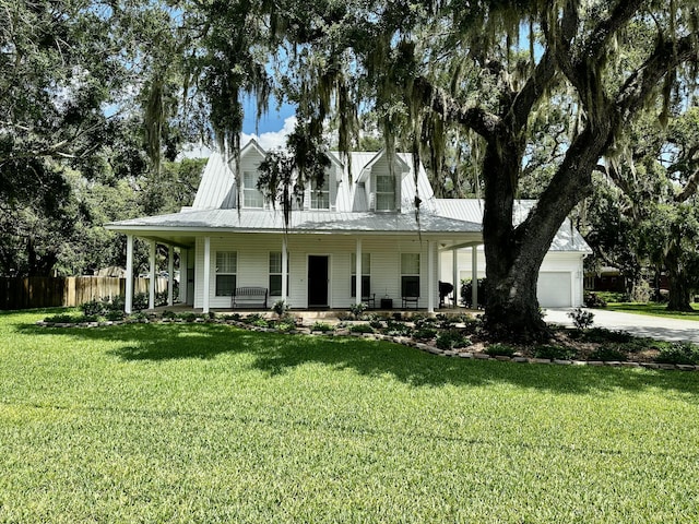 farmhouse-style home featuring a front lawn, covered porch, and a garage