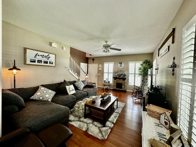 living room with a fireplace, hardwood / wood-style floors, a textured ceiling, and ceiling fan