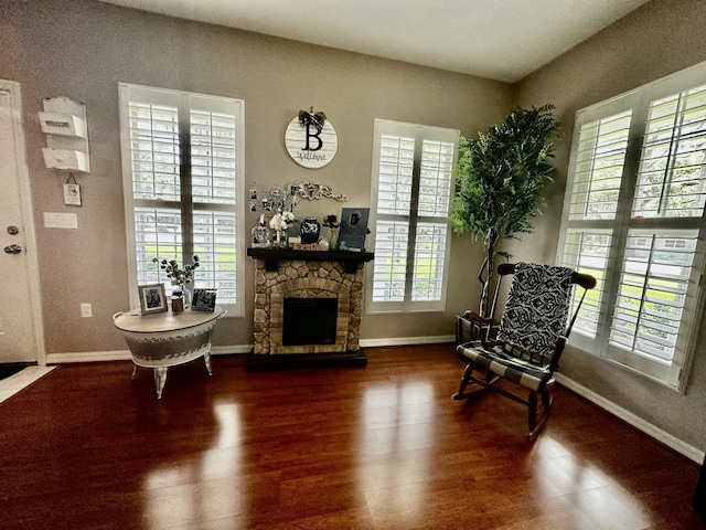 sitting room with plenty of natural light, dark hardwood / wood-style floors, and a stone fireplace