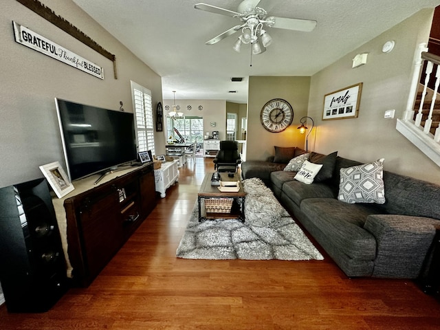 living room featuring ceiling fan with notable chandelier and hardwood / wood-style flooring