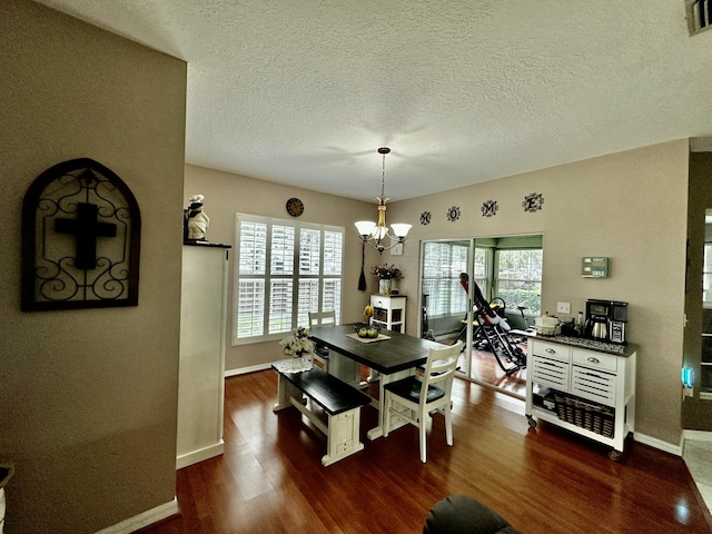 dining space featuring a textured ceiling, dark hardwood / wood-style floors, and a notable chandelier