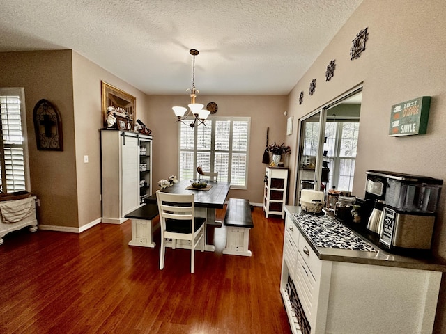 dining space featuring dark hardwood / wood-style floors, a textured ceiling, and an inviting chandelier