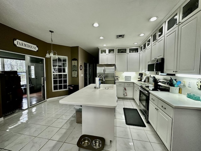 kitchen featuring a kitchen island with sink, white cabinets, decorative light fixtures, stainless steel appliances, and a chandelier