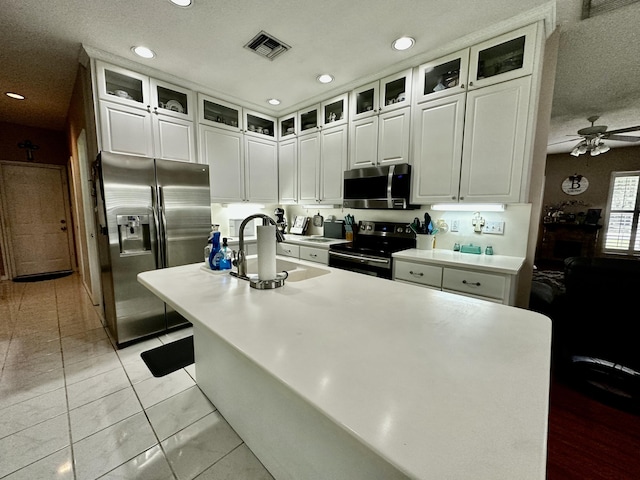 kitchen with white cabinets, sink, ceiling fan, light tile patterned flooring, and stainless steel appliances