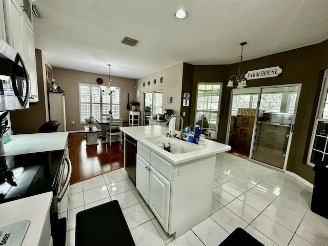 kitchen with white cabinets, sink, hanging light fixtures, an island with sink, and a chandelier