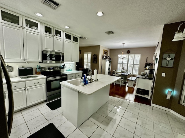 kitchen with sink, black range with electric cooktop, pendant lighting, a kitchen island with sink, and white cabinets