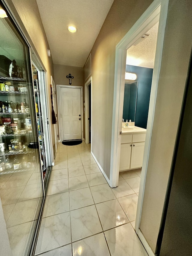 corridor with sink and a textured ceiling