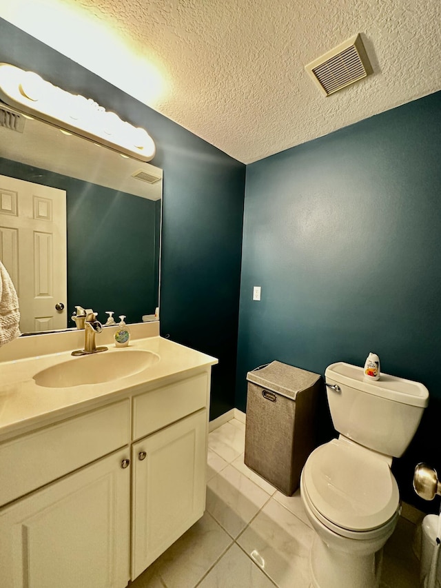 bathroom featuring toilet, a textured ceiling, vanity, and tile patterned floors