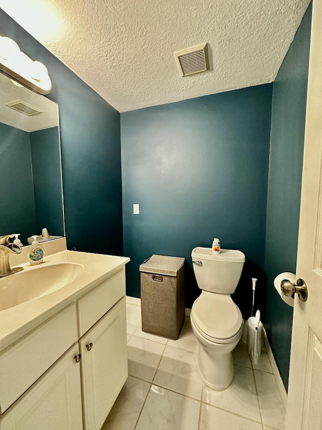 bathroom with tile patterned flooring, vanity, a textured ceiling, and toilet