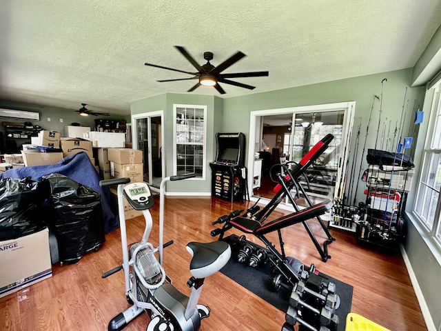 workout area featuring hardwood / wood-style floors, ceiling fan, and a textured ceiling