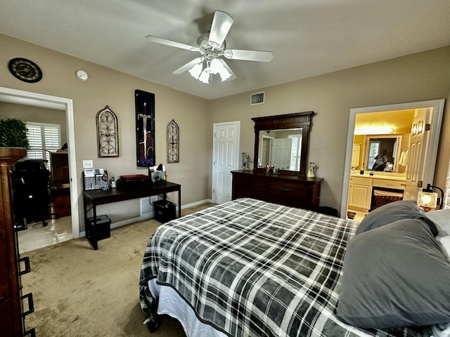 bedroom with ceiling fan, light colored carpet, and connected bathroom