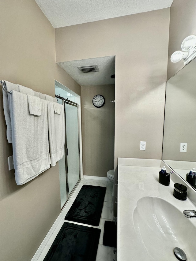 bathroom featuring a shower with door, vanity, a textured ceiling, and toilet