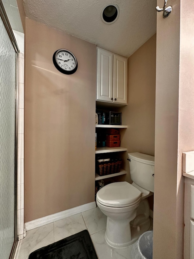 bathroom with tile patterned floors, a textured ceiling, toilet, and a shower with shower door