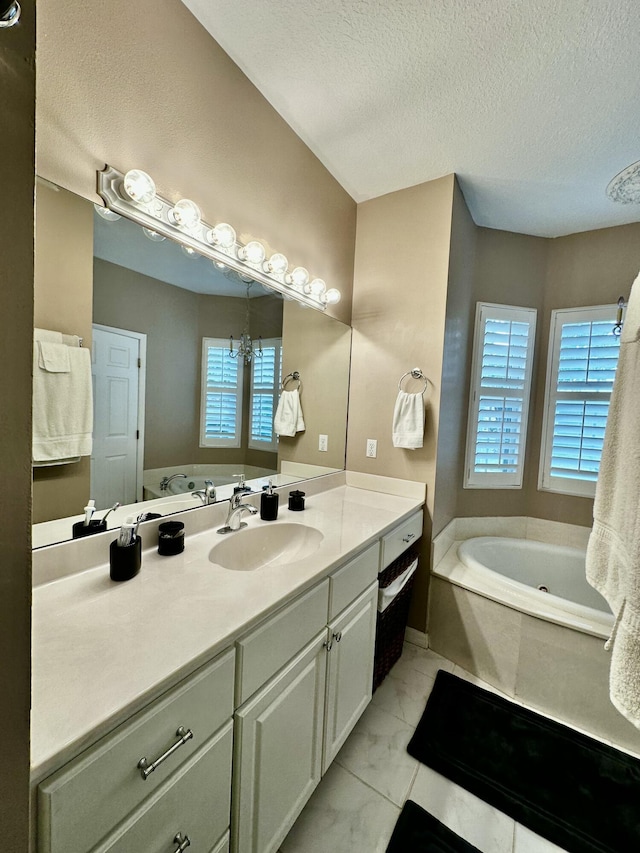 bathroom with a textured ceiling, vanity, and a bathtub