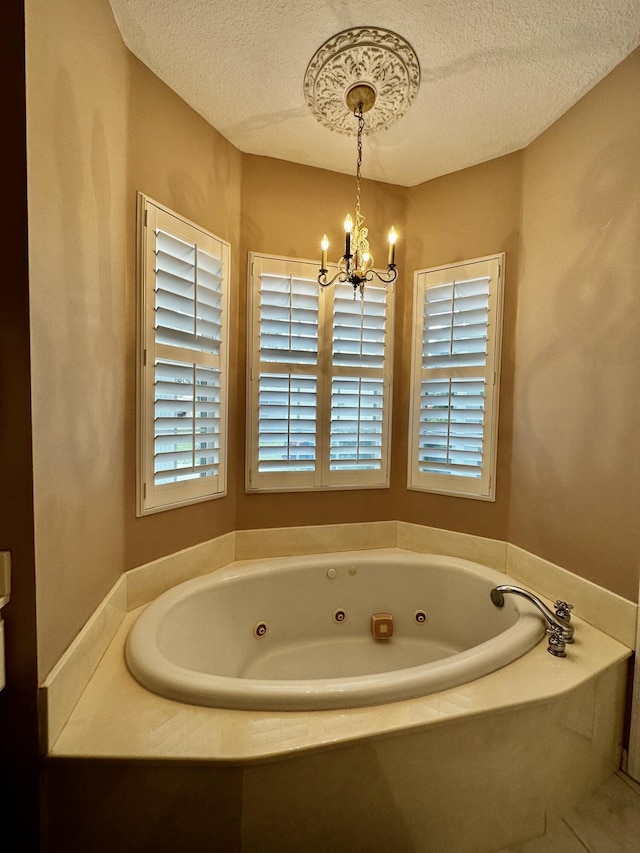 bathroom featuring a tub, a chandelier, and a textured ceiling