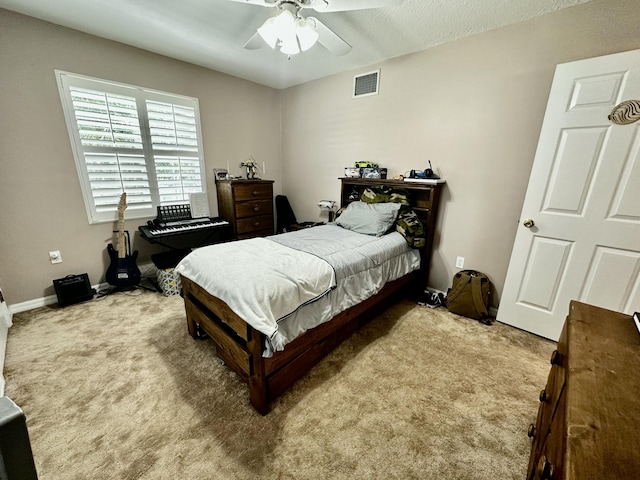 bedroom featuring ceiling fan, light carpet, and a textured ceiling