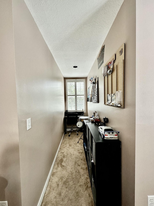 corridor with light colored carpet and a textured ceiling