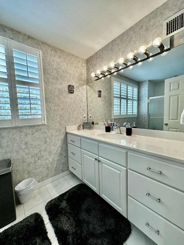 bathroom with tile patterned flooring, a textured ceiling, vanity, and an enclosed shower