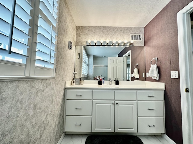 bathroom with a textured ceiling, vanity, and a shower with shower door