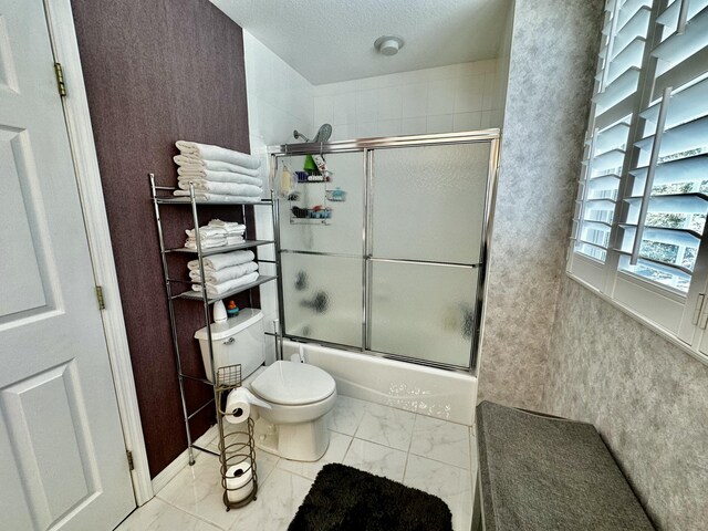 bathroom featuring shower / bath combination with glass door and toilet