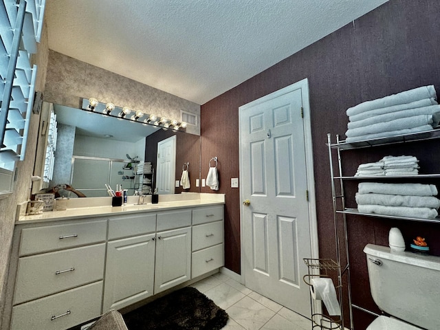 bathroom featuring toilet, vanity, a textured ceiling, and walk in shower