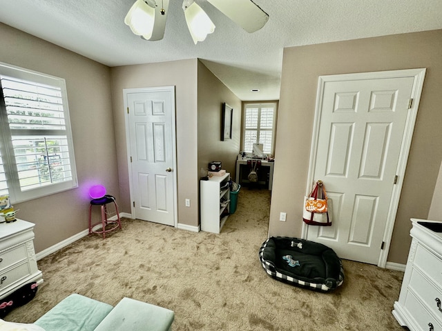 interior space featuring light carpet, a textured ceiling, and ceiling fan