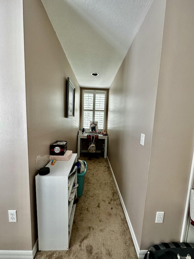 hallway with light colored carpet and a textured ceiling