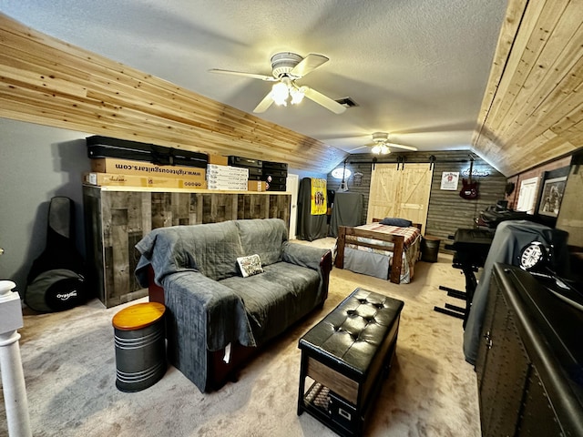 interior space featuring wood ceiling, a textured ceiling, ceiling fan, a barn door, and lofted ceiling