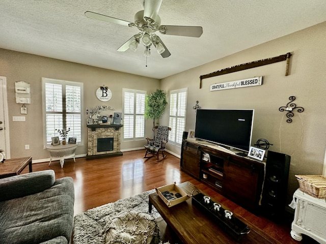 living room featuring a textured ceiling, dark hardwood / wood-style floors, ceiling fan, and a fireplace