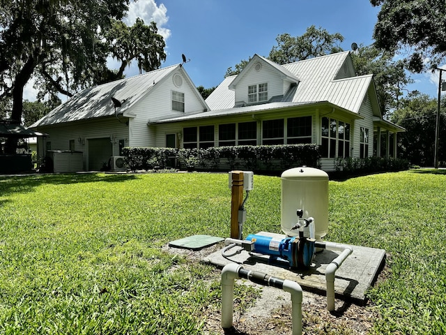 rear view of house with a lawn, central AC unit, and a garage