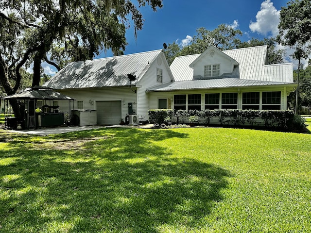 back of property with a gazebo, central AC unit, a garage, and a yard