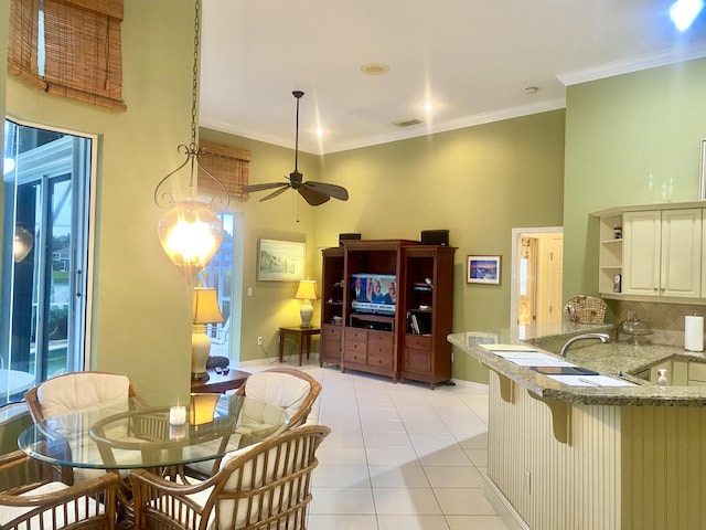 kitchen featuring kitchen peninsula, ceiling fan, crown molding, pendant lighting, and a breakfast bar area