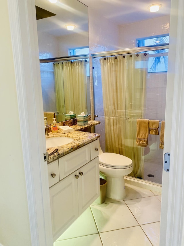 bathroom featuring tile patterned flooring, vanity, a shower with shower door, and toilet