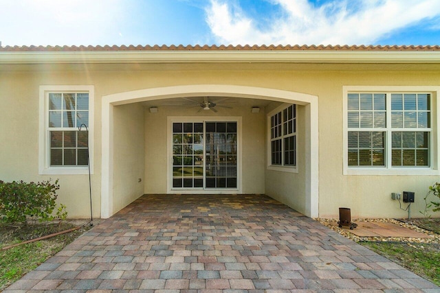 property entrance with a patio area, ceiling fan, and stucco siding