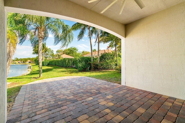 view of patio featuring a water view, ceiling fan, and fence