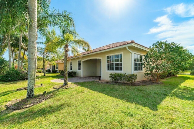 view of front of house with a front yard, a tile roof, and stucco siding