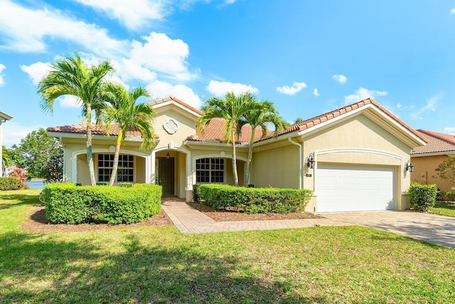 mediterranean / spanish home featuring a front lawn, an attached garage, a tile roof, and stucco siding