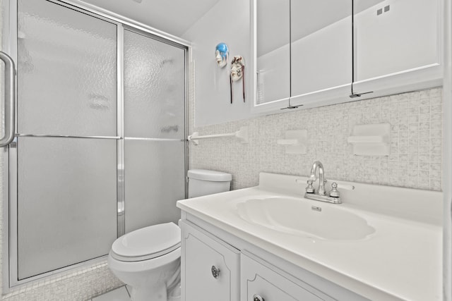 bathroom with vanity, toilet, a shower with door, and tile walls