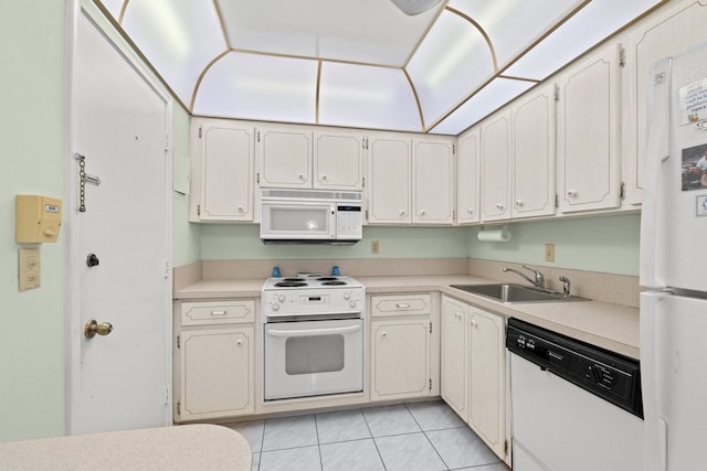 kitchen with white cabinetry, sink, light tile patterned flooring, and white appliances