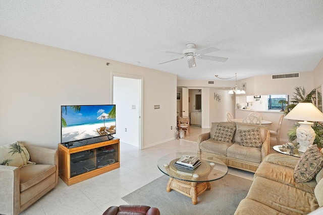 living room featuring ceiling fan with notable chandelier and a textured ceiling