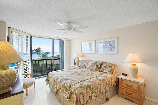 bedroom featuring access to exterior, ceiling fan, expansive windows, a textured ceiling, and light tile patterned flooring