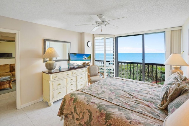 bedroom featuring expansive windows, ceiling fan, access to exterior, light tile patterned floors, and a textured ceiling